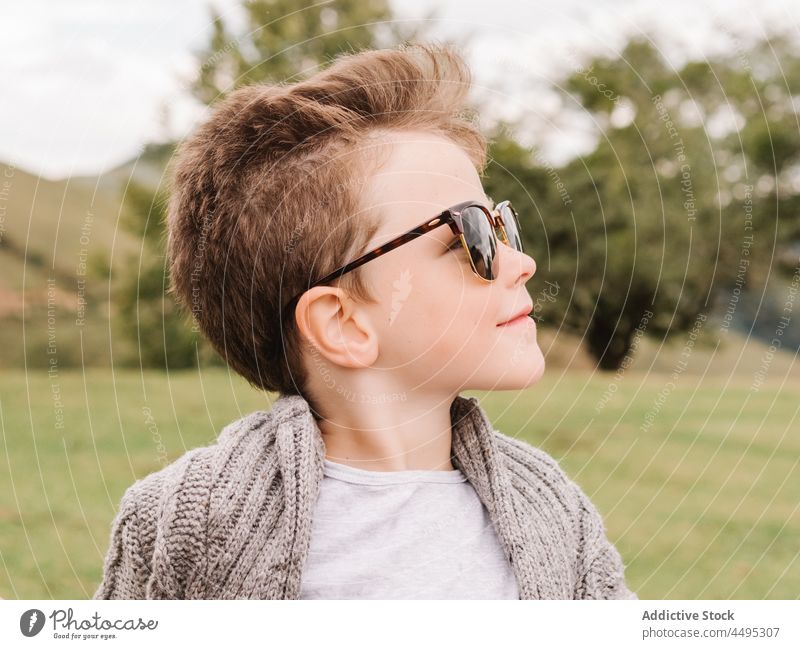Stilvoller Junge mit Sonnenbrille in der Landschaft sitzend Kind Kindheit Mode Natur Freizeit Baum Feld Inhalt grün trendy sorgenfrei Sommer froh Pflanze