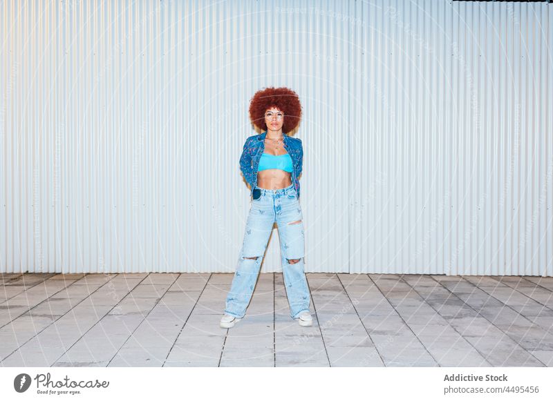 Modische Frau mit Afrofrisur steht in der Nähe der Wand Afro-Look Stil Mode trendy Bekleidung Vorschein Outfit Straße Frisur Sonnenbrille Accessoire Top
