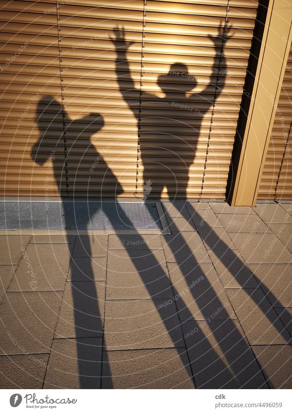 Schattenspiel Schattenspiele Licht und Schatten 2 Personen Mann und Frau Aktion Interaktion Theater Fenster Lamellen Gehsteig Boden draußen erhobene Hände