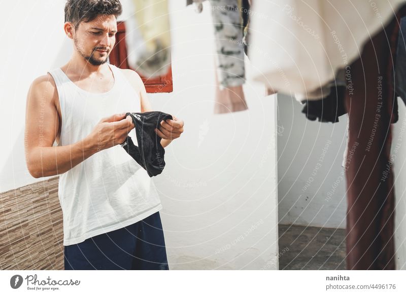 Junger Mann macht die Wäsche zu Hause Wäscherei heimwärts Kleidung Waschen Sauberkeit frisch Wäsche waschen backyarkd Familie Baby männlich modern Maskulinität