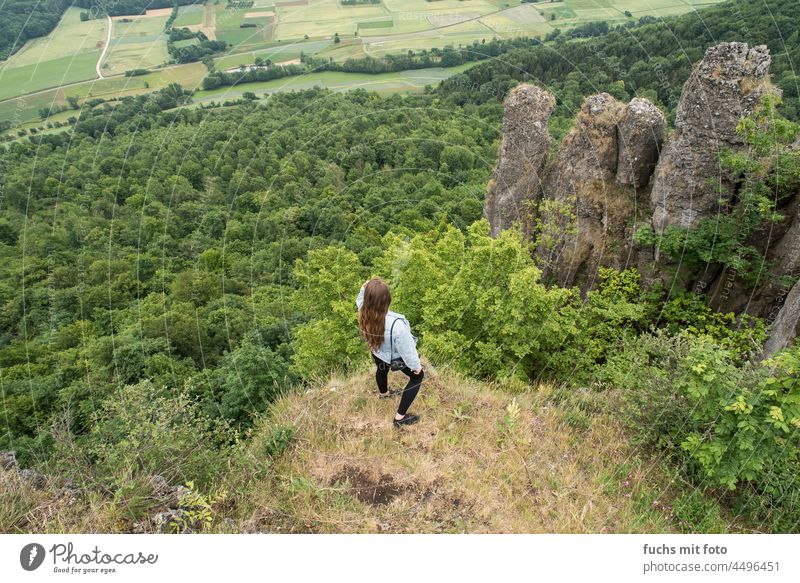 Ausblick, Junge Frau blickt in die Ferne, Outdoor Weitblick Natur Berge Felder Grün lange Haare Felsen Fränkische Schweiz Jeansjacke denim leggins wandern