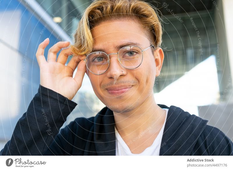 Lächelnder Mann mit Brille auf der Straße Stil Gebäude Vorschein Schüler Großstadt anhaben klug männlich ausrichten lässig froh Inhalt positiv jung Stadt Jugend