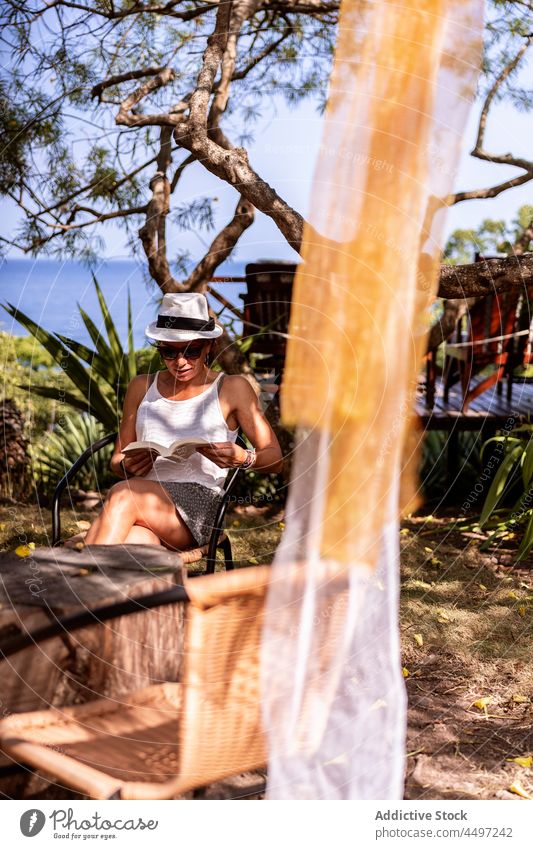 Frau sitzt und liest ein Buch auf einer tropischen Insel im Meer lesen Urlaub Sommer sitzen besinnlich nachdenklich São Tomé und Príncipe Afrika Baum Pflanze