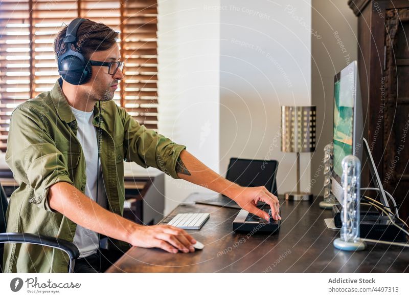 Mann mit Kopfhörern bei der Arbeit am Computer benutzend Arbeitsplatz Arbeitsbereich Konzentration professionell Atelier Maus männlich Gerät Job Beruf Tisch