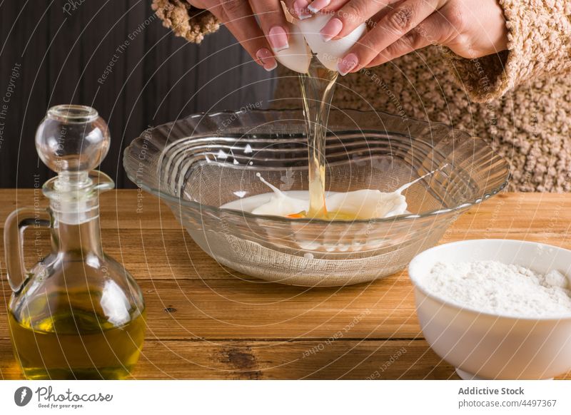 Unbekannte Frau schlägt Ei in Schüssel mit Milch auf Pause Mehl melken Erdöl Crêpe Produkt Küche Koch Rezept vorbereiten Kannen Tisch Schalen & Schüsseln Licht