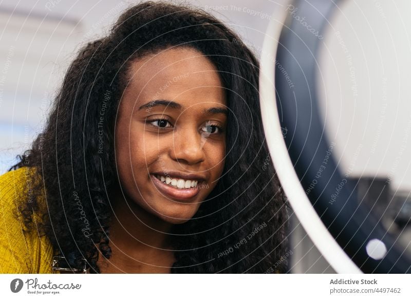 Lächelnde schwarze Bloggerin dreht Video zu Hause Frau vlog Aufzeichnen Smartphone Influencer Lampe Zahnfarbenes Lächeln Glück Afroamerikaner Stativ Apparatur