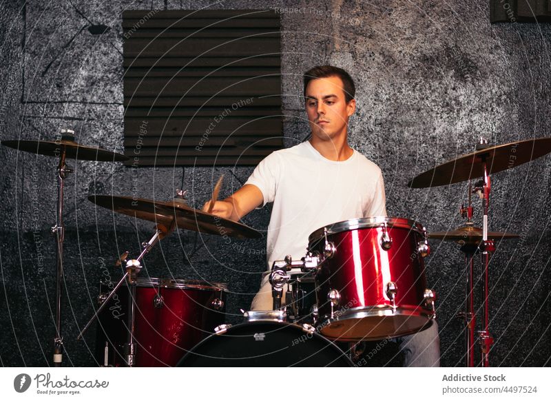 Männlicher Schlagzeuger, der in einem hellen Studio spielt Mann Trommel Instrument spielen Absturz ausführen Club Musiker Fähigkeit Talent professionell