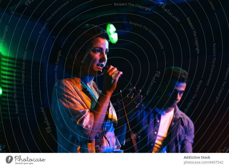 Band spielt Instrumente und singt in einem Neon-Club ausführen singen Gesang Mann Frau neonfarbig Musik Mikrofon Konzert glühen professionell Sänger Musiker