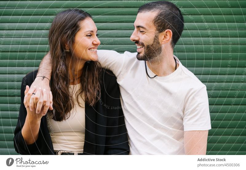 Fröhliches liebendes ethnisches Paar, das sich auf der Straße lächelnd ansieht Lachen Umarmung Liebe heiter Partnerschaft Zusammensein romantisch Glück