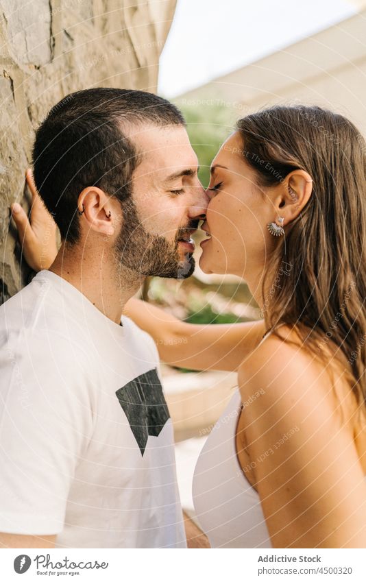 Liebendes ethnisches Paar küsst sich in der Nähe einer Hauswand auf der Straße Kuss Umarmen Augen geschlossen Wand Stein romantisch Partnerschaft Zuneigung