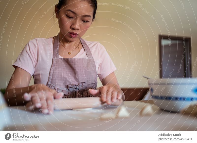 Hausfrau knetet Teig in der Küche Frau asiatisch Chinesisch kneten Teigwaren Knödel vorbereiten Lebensmittel selbstgemacht Nudelholz Koch kulinarisch Rezept