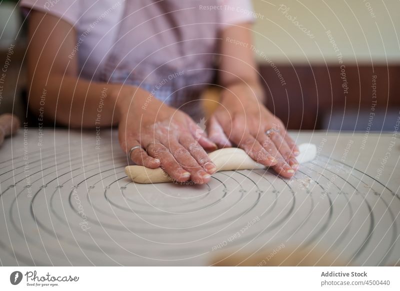 Crop Hausfrau rollt Teig mit den Händen Frau rollen Teigwaren Koch Küche Knödel selbstgemacht vorbereiten Lebensmittel Prozess Rezept kulinarisch lässig Schürze