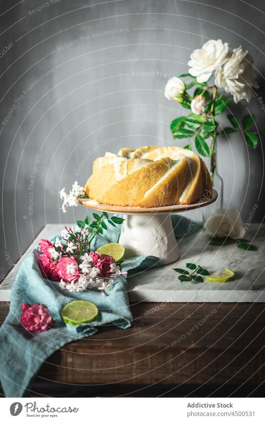 Limettenbiskuit auf Teller neben Blumen und Limettenscheiben Kuchen Kalk Schwamm Dessert Konditorei Zitrusfrüchte Biskuit gebacken geschmackvoll Frucht