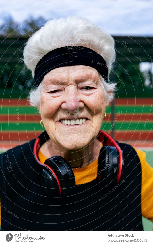 Glückliche Seniorin in Sportkleidung und Kopfhörern Frau meloman Sportpark Hobby Gesunder Lebensstil Musik auflehnen informell durchbohrt Training reif positiv