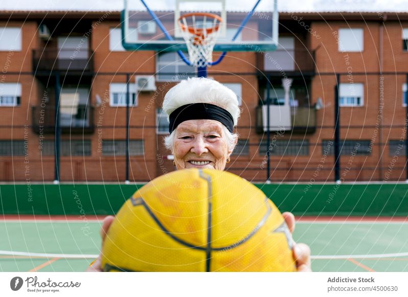 Fröhliche Seniorin mit Basketball auf dem Spielplatz Frau Ball spielen Sportpark Hobby Gesunder Lebensstil Training reif Lächeln heiter positiv Aktivität