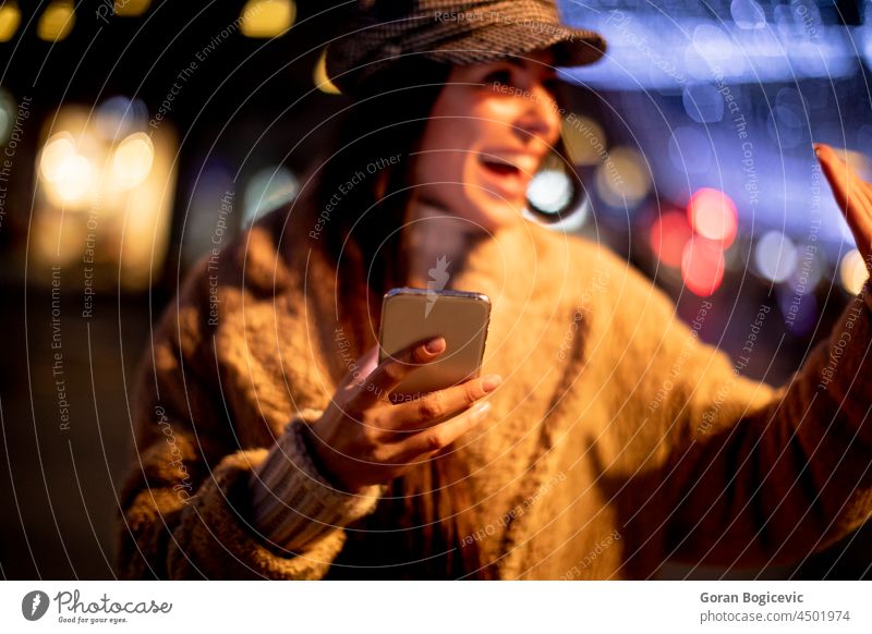 Hübsche junge Frau benutzt ihr Handy auf der Straße zur Weihnachtszeit Tasche schön Browsen Verschlussdeckel Funktelefon Weihnachten Großstadt Stadtbild