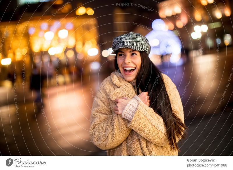 Hübsche junge Frau auf der Straße in der kalten Weihnachtsnacht Waffen schön Verschlussdeckel Weihnachten Großstadt Stadtbild Kleidung Konzept gekreuzt