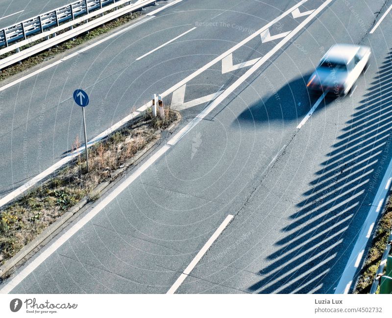 Geradeaus oder schnell unterwegs, auf einer ziemlich leeren Bundesstraße im Sonnenschein Linie Sonnenlicht Richtung von oben Fahrzeug gerade weiß Streifen