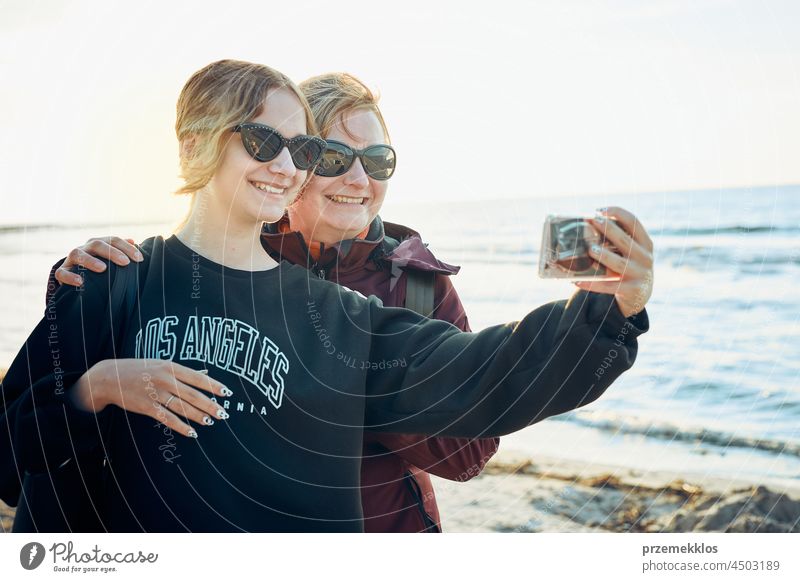 Glückliche Frauen, die während ihres Sommerurlaubs einen Videoanruf mit ihrem Smartphone tätigen Anruf Telefon Talkrunde gestikulieren Gruß unter Foto Selfie