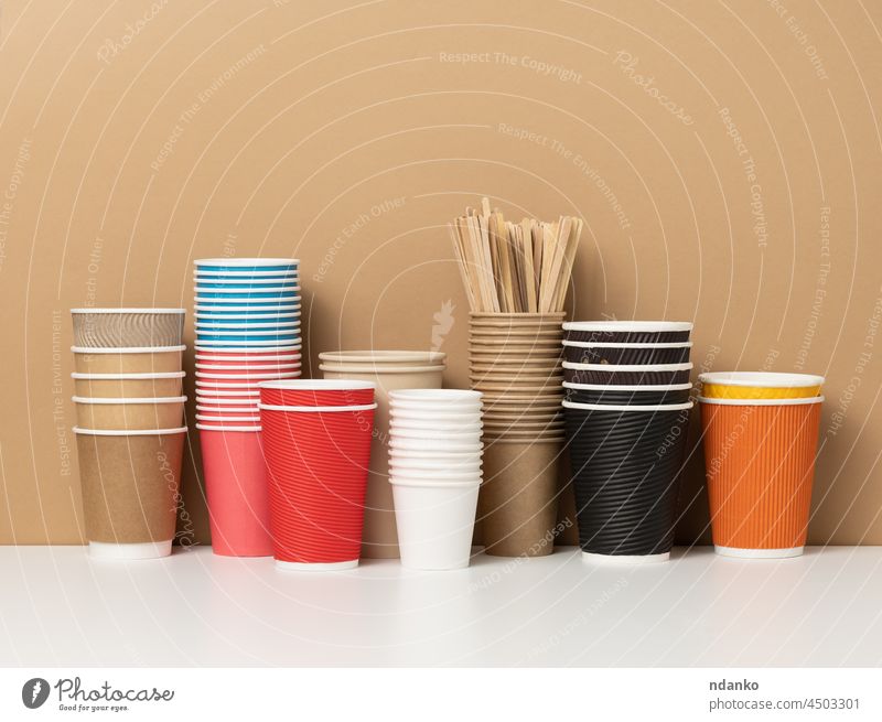 Stapel von verschiedenen Einweg-Pappbechern für Getränke, Kaffee und Tee auf einem weißen Tisch. Behälter für Getränke zum Mitnehmen americano blanko blau