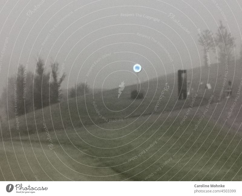 Eine leuchtende Uhr trotzt einem nebligen Morgen auf einem Golfplatz Nebel trist Menschenleer Außenaufnahme Natur Landschaft Textfreiraum oben Umwelt Tag grau