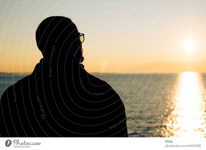 Rückansicht eines Mannes, der im die Sonne über dem Meer blickt Sonnenaufgang Horizont Silhouette Wasser Himmel Wasseroberfläche Sonnenlicht Ferne