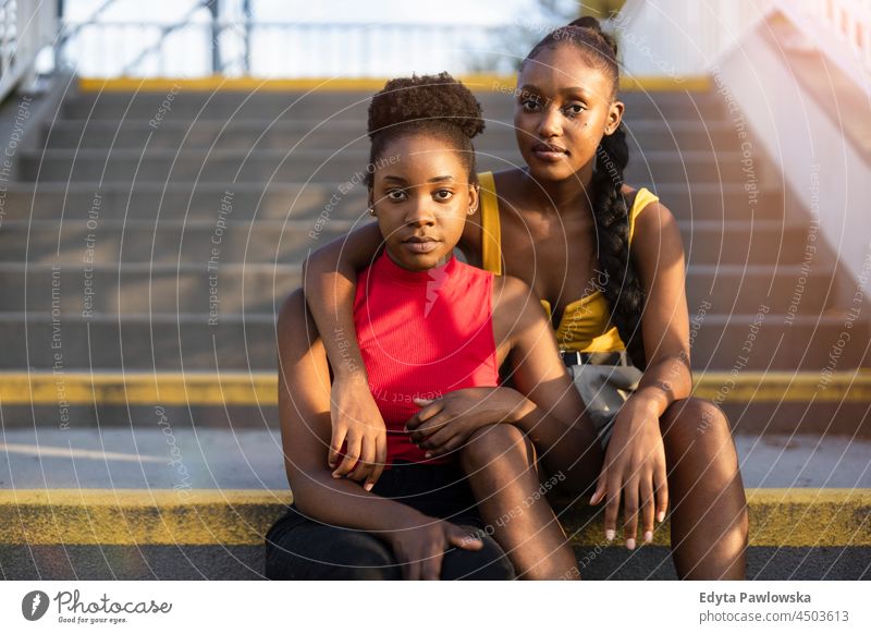 Porträt von zwei jungen Frauen auf der Treppe sitzend Jugend Schwesternschaft attraktiv Freundinnen echte Menschen Jahrtausende cool Vielfalt schwarz