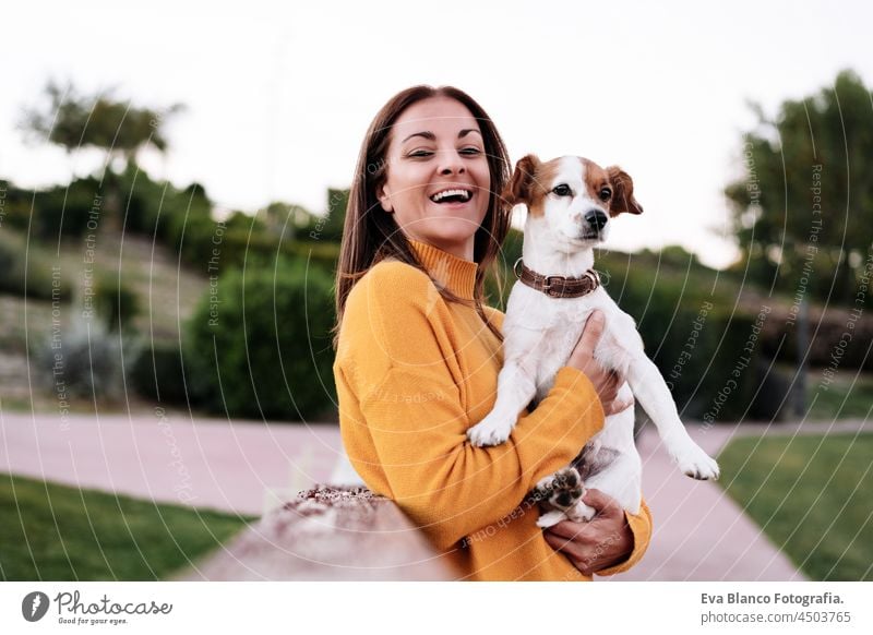glückliche kaukasische Frau, die Spaß mit Jack Russell Hund im Park, Frau hält Haustier im Herbst Saison. Haustiere und Liebe Konzept jack russell Glück Kuss