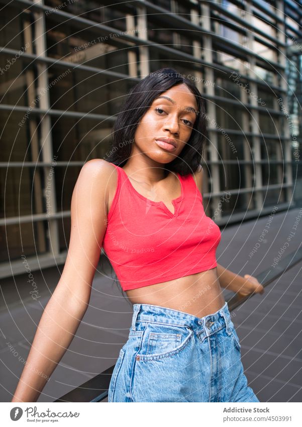 Stilvolle schwarze Frau lehnt an einem Geländer in der Stadt Straße Großstadt urban Gebäude Kleidung Outfit Reling modern Afroamerikaner Haus attraktiv