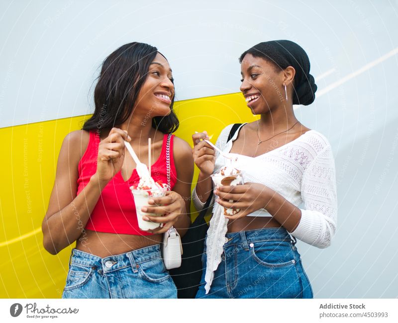 Fröhliche schwarze Frauen essen Eis Freundschaft Speiseeis Dessert süß Leckerbissen Bonden Straße Zeitvertreib schwelgen freie Zeit Afroamerikaner Lifestyle
