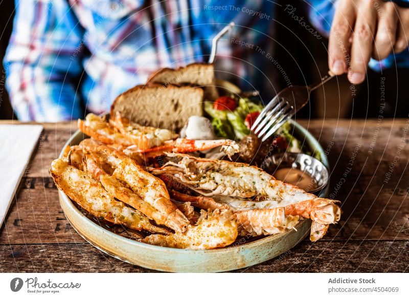 Mann isst gegrillte Riesengarnelen mit Brot und Salat Restaurant essen Speise Gabel Lebensmittel Krabbe Meeresfrüchte geschmackvoll männlich lecker Island Tisch