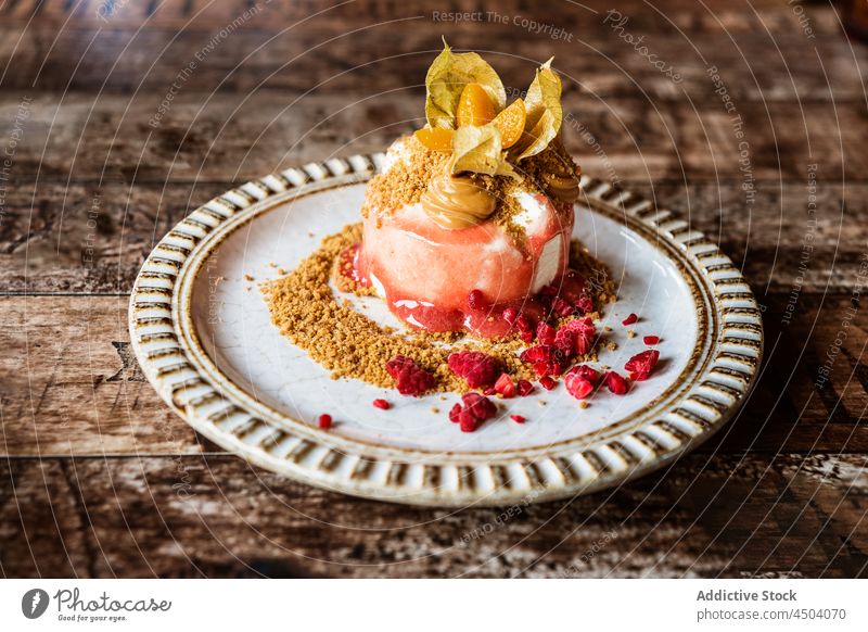 Leckeres Dessert mit Physalis auf einem Teller auf einem Holztisch Beeren Lebensmittel geschmackvoll Sahne süß Krümel dienen lecker Tisch Keks Kuchen