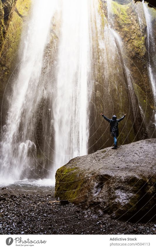 Anonymer Reisender genießt die Energie eines mächtigen Wasserfalls in einer felsigen Schlucht Person Natur Tourist ausdehnen bewundern genießen malerisch