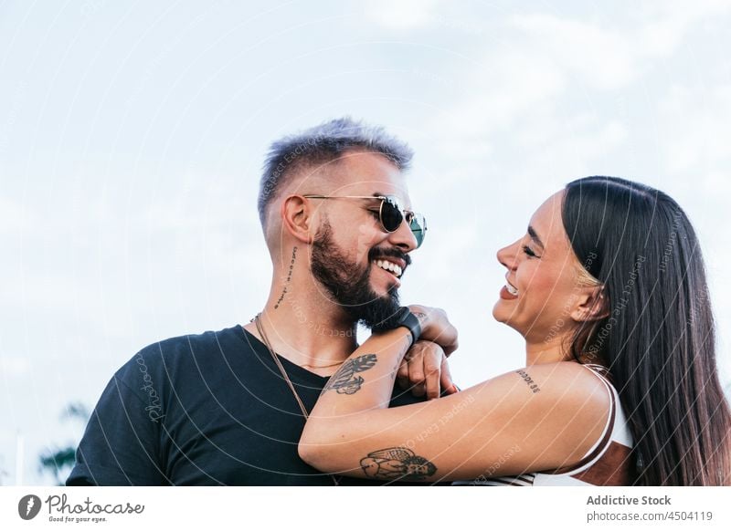 Glückliches Paar umarmt und lacht auf der Straße Lachen Umarmung heiter Umarmen Sonnenbrille positiv Spaß Mann Frau Freundin Partnerschaft tagsüber lässig