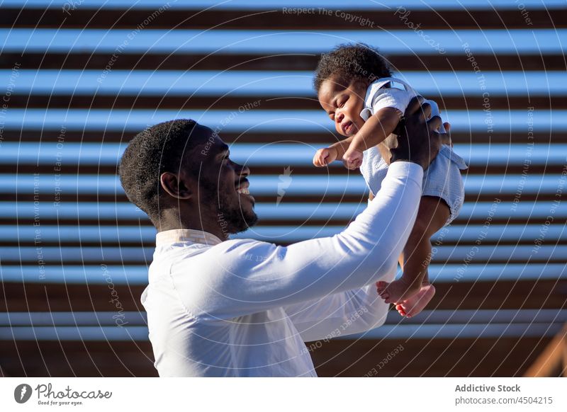 Schwarzer Vater trägt kleines Kind auf Händen Mann Baby Eltern wenig Glück Vaterschaft heben Papa männlich Afroamerikaner schwarz Straße Kindheit Elternschaft