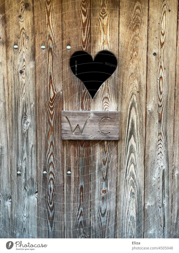 Holztüre eines WCs mit Herz. Plumsklo. plumsklo Toilette alt Türe Klo Schild geschrieben Guckloch