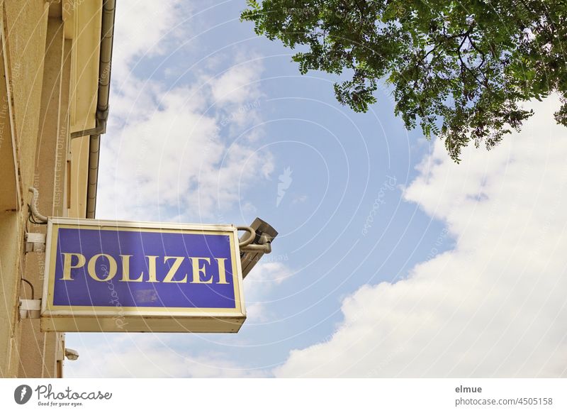 Schilder I Hinweisschild - Polizei - und eine Überwachungskamera am Eingang der Polizeiwache Gebäude Froschperspektive Baum Leuchtkasten Polizeirevier
