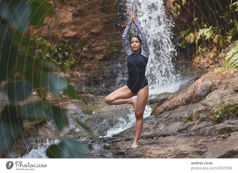 Frau macht Yoga auf einem im Wald mit einem Wasserfall im Hintergrund Felsen Fluss Baum grün Natur Außenaufnahme Tag Landschaft Sonnenlicht tropisch
