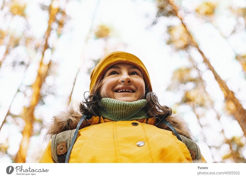 Porträt eines fröhlichen kaukasischen Touristenmädchens in einer orangefarbenen Jacke und Hut. Wandern im Herbstwald. Positive Gefühle. Outdoor-Aktivität. Wandern im Wald in der Herbstzeit. Nahaufnahme