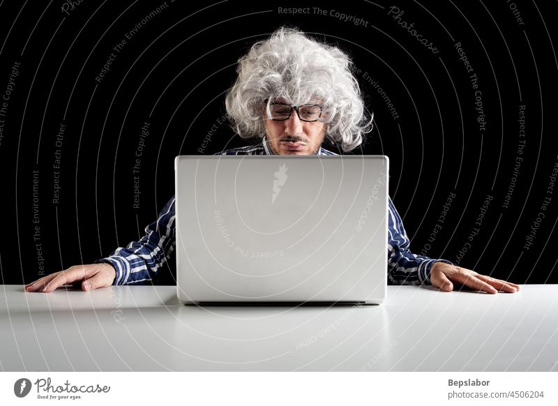 Ein Boomer-Senior, der konzentriert am Schreibtisch sitzt und auf einen Laptop schaut Person ratlos ungewiss zögernd männlich Kaukasier Computer Mann