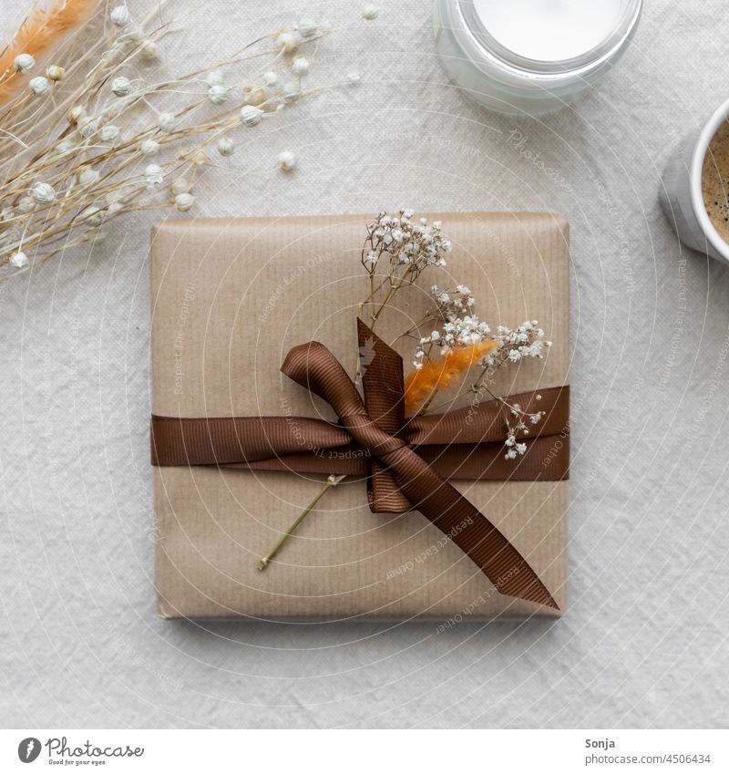 Draufsicht auf ein Geschenk Paket mit einer braunen Schleife und Trockenblumen Geschenkband Geburtstag schenken Verpackung Vorfreude Stimmung