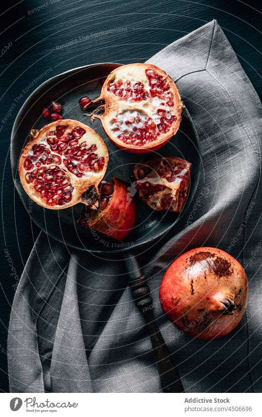 Reifer Granatapfel in der Pfanne auf dem Tisch reif Frucht Vitamin Gesundheit Lebensmittel Hälfte Samen hacken Küche Tischwäsche zerknittern ganz geschmackvoll