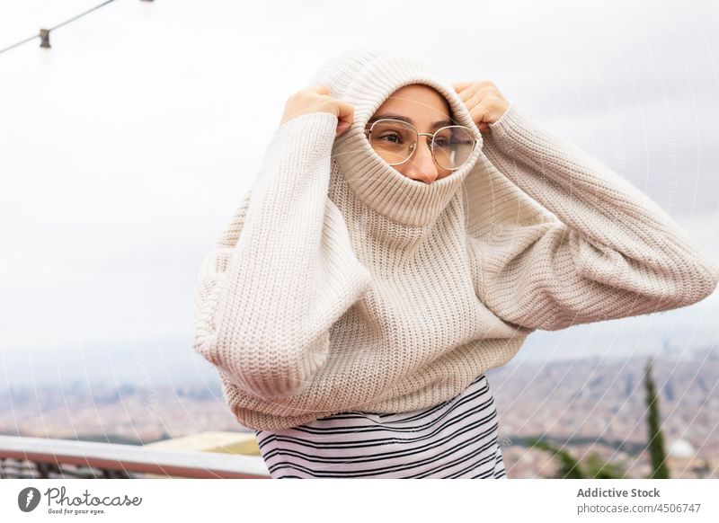 Frau zieht warmen Pullover an Aussichtspunkt Großstadt angezogen kalt Wind Wochenende positiv Saison verkleiden Strickwaren gemütlich Inhalt Brille Stil urban