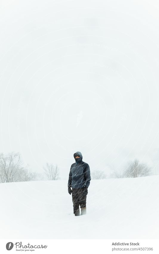 Mann in Oberbekleidung stehend in verschneiter Winternatur Schneefall Schneesturm kalt Natur Dunst bedeckt Umwelt männlich Winterzeit warme Kleidung Tal laublos