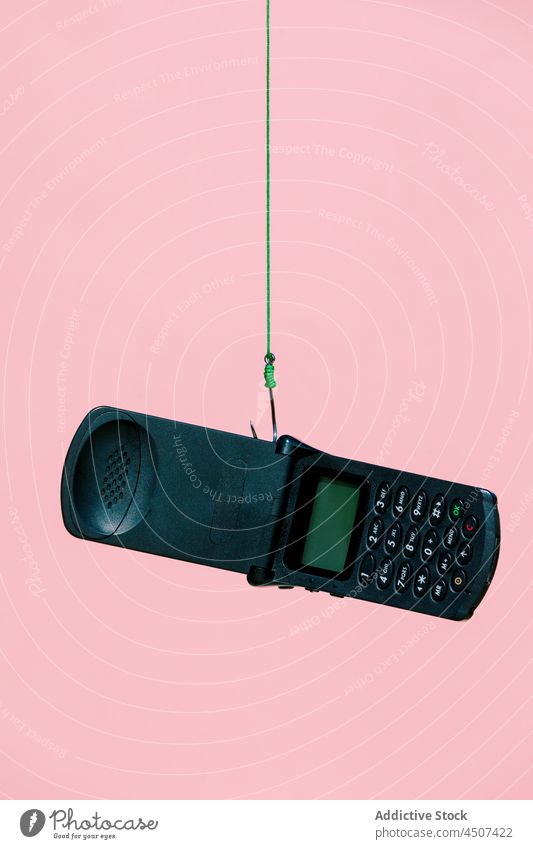 Altmodisches Flip-Mobile am Haken hängend Telefon altmodisch veraltet verwendet Seil Konzept Gerät schwarz Stil Ausgelaufen lebhaft Atelier Farbe Nostalgie
