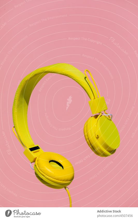 Gelbe Kopfhörer auf rosa Hintergrund modern Musik zuhören Drahtlos farbenfroh hell Klang Gerät Audio pulsierend Gesang lebhaft hängen schweben unterhalten
