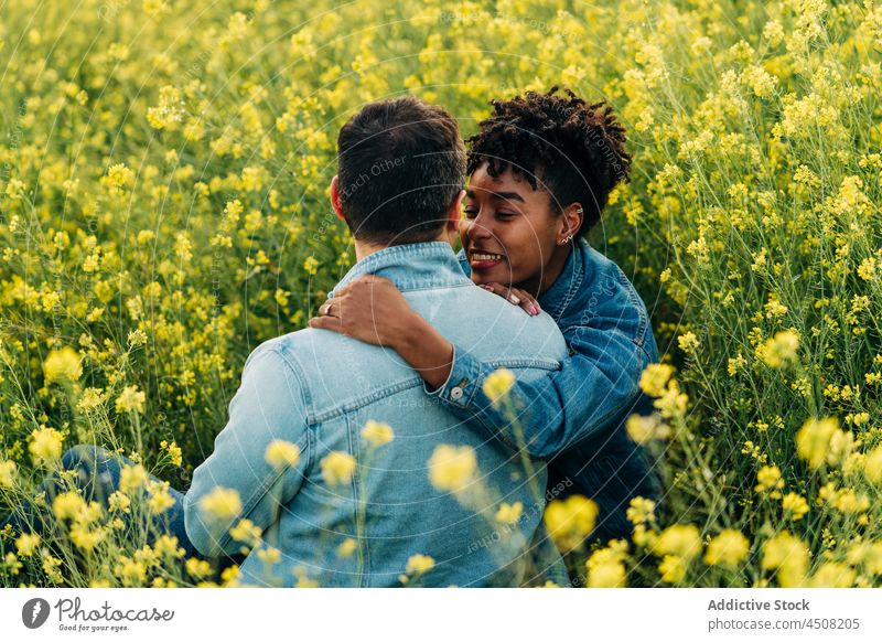 Glückliches junges buntes Paar, das sich auf einer Wiese im Sonnenlicht ansieht die sich gegenseitig ansehen Termin & Datum romantisch Liebe Zusammensein