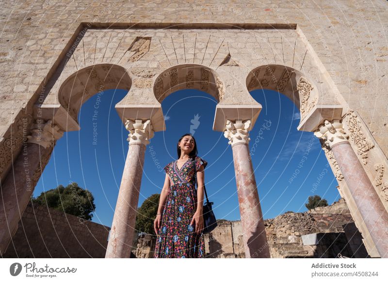 Asiatische Frau in der Nähe des historischen Portikus stehend mittelalterlich antik Stadt gealtert Bogen Tourist Architektur Straße beobachten Reise bewundern