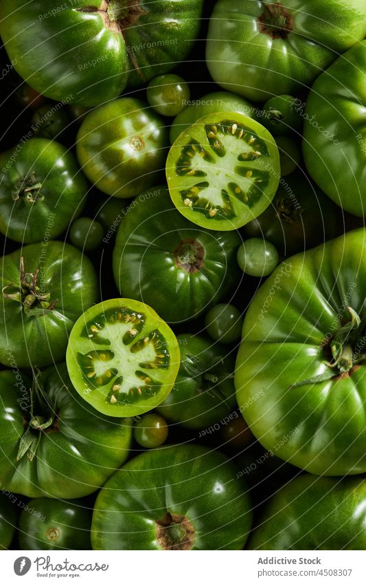 Geschnittene Tomate auf einem Haufen unreifer Tomaten Kirschtomate Streuung Scheibe Gemüse Ernte Vitamin viele Landschaft Ackerbau Agronomie Garten Bauernhof