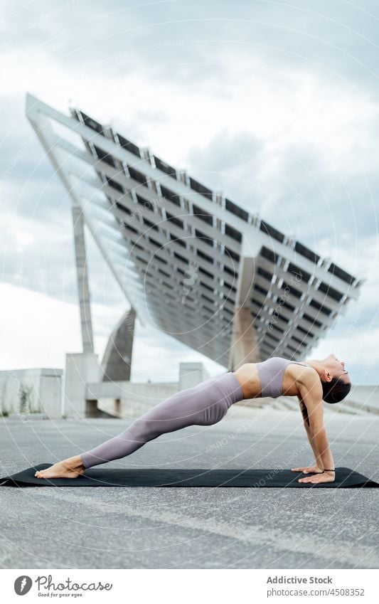 Energetische Frau macht aufwärts plank asana auf Straße Aufwärtshaken Purvottanasana Yoga Asana solar Panel Übung Training üben Energie beweglich Dame modern